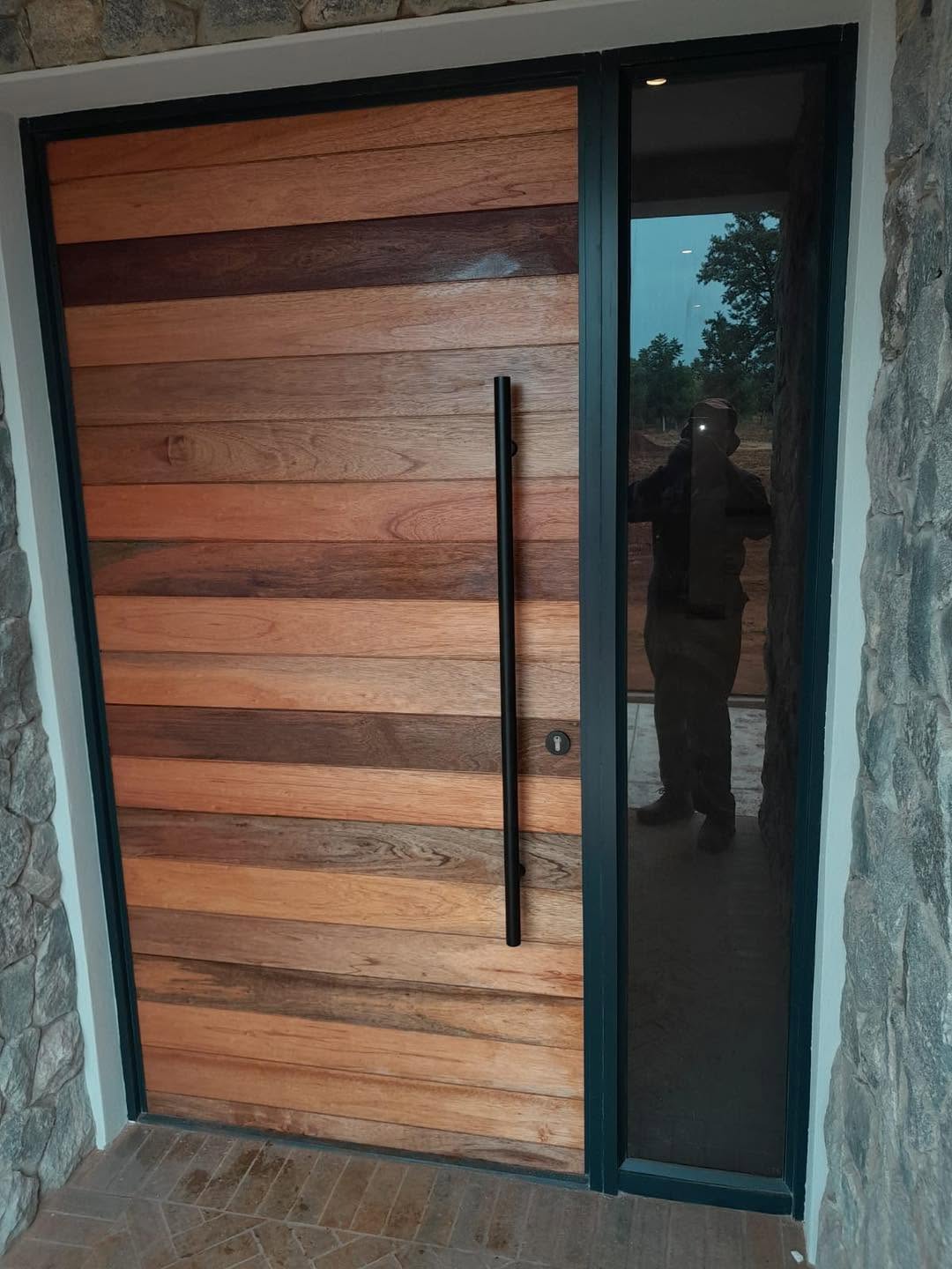 Kiaat pivot front door with sidelight on stone facade
