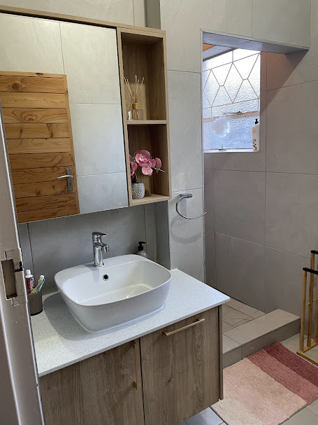Oak vanity with open shelving, vessel basin and mirrored cabinet