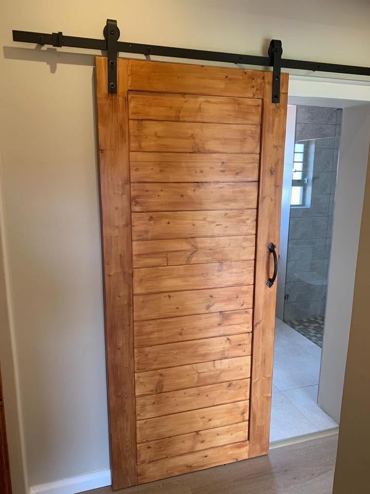 Rustic pine sliding barn door at bathroom entrance