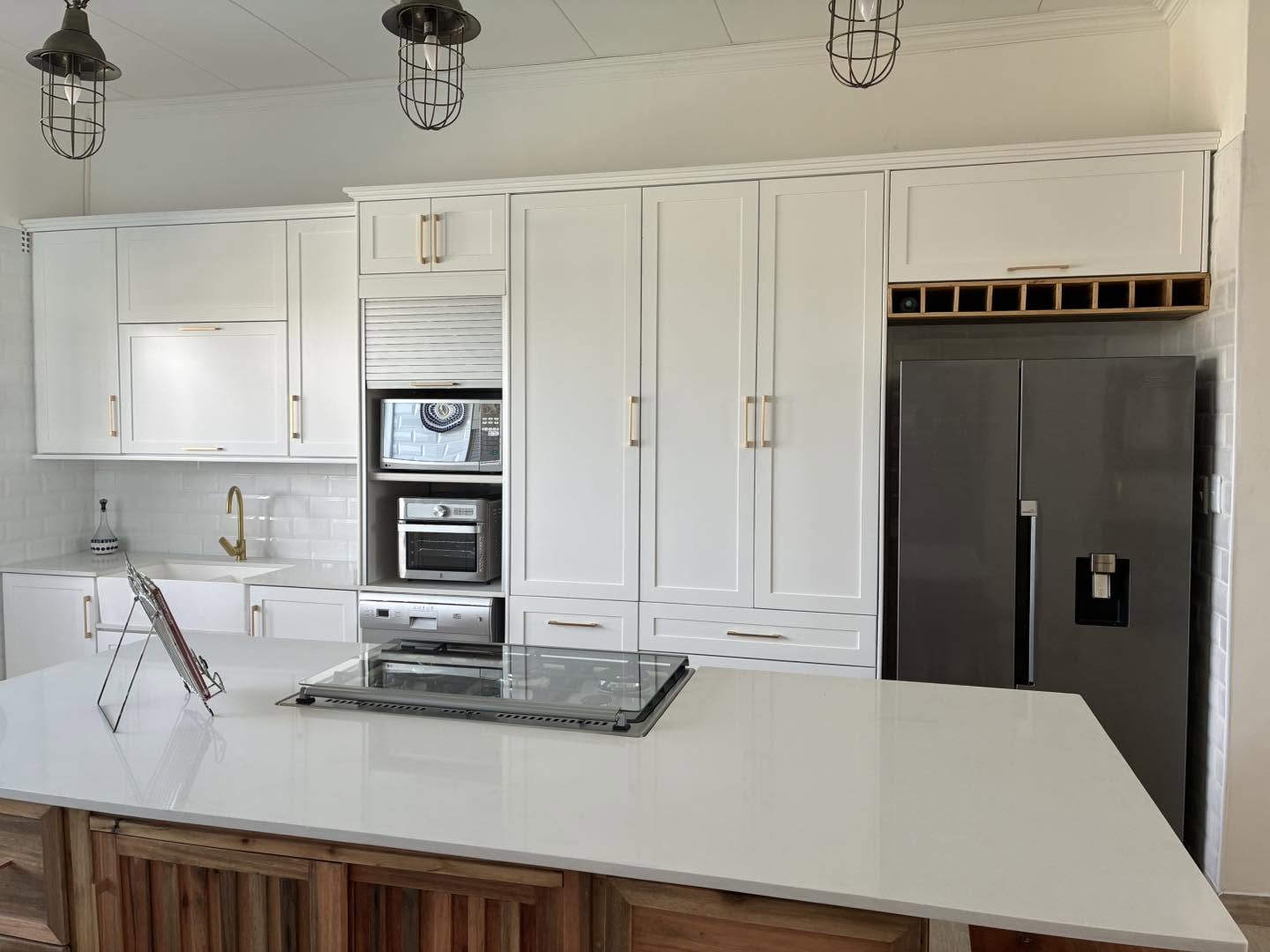 White shaker kitchen with brass handles and timber island