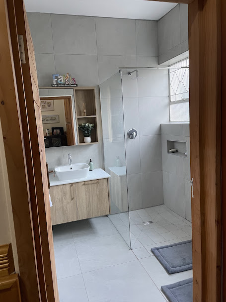 Walk-in shower with frameless glass and oak floating vanity
