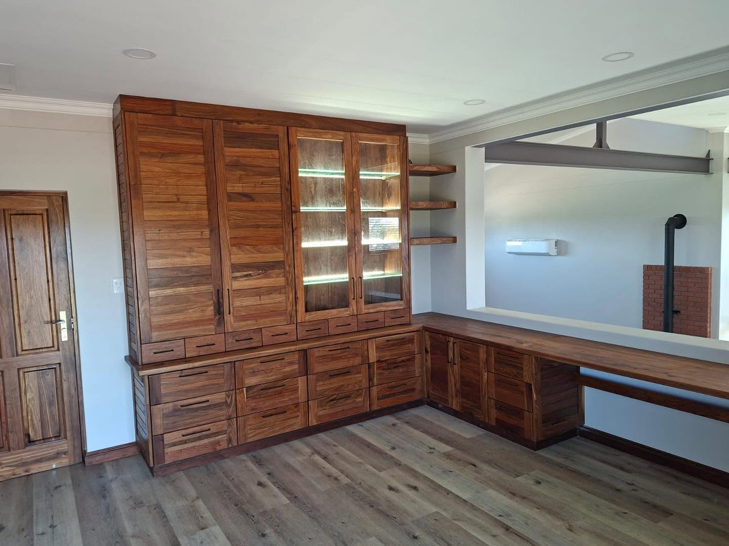 Solid kiaat built-in display cabinet with LED-lit glass shelving and desk