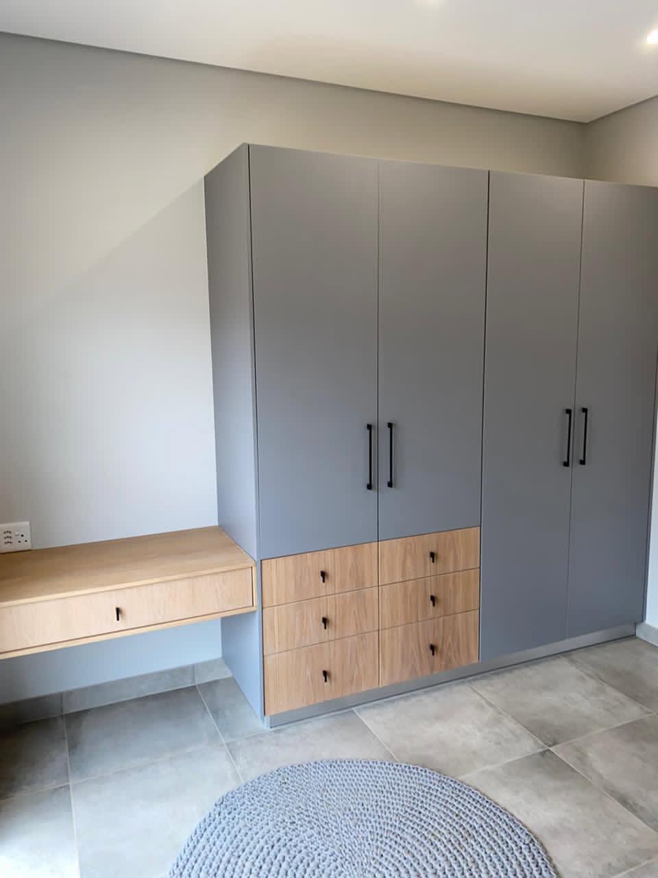 Grey two-tone bedroom cupboards with oak drawers and floating desk
