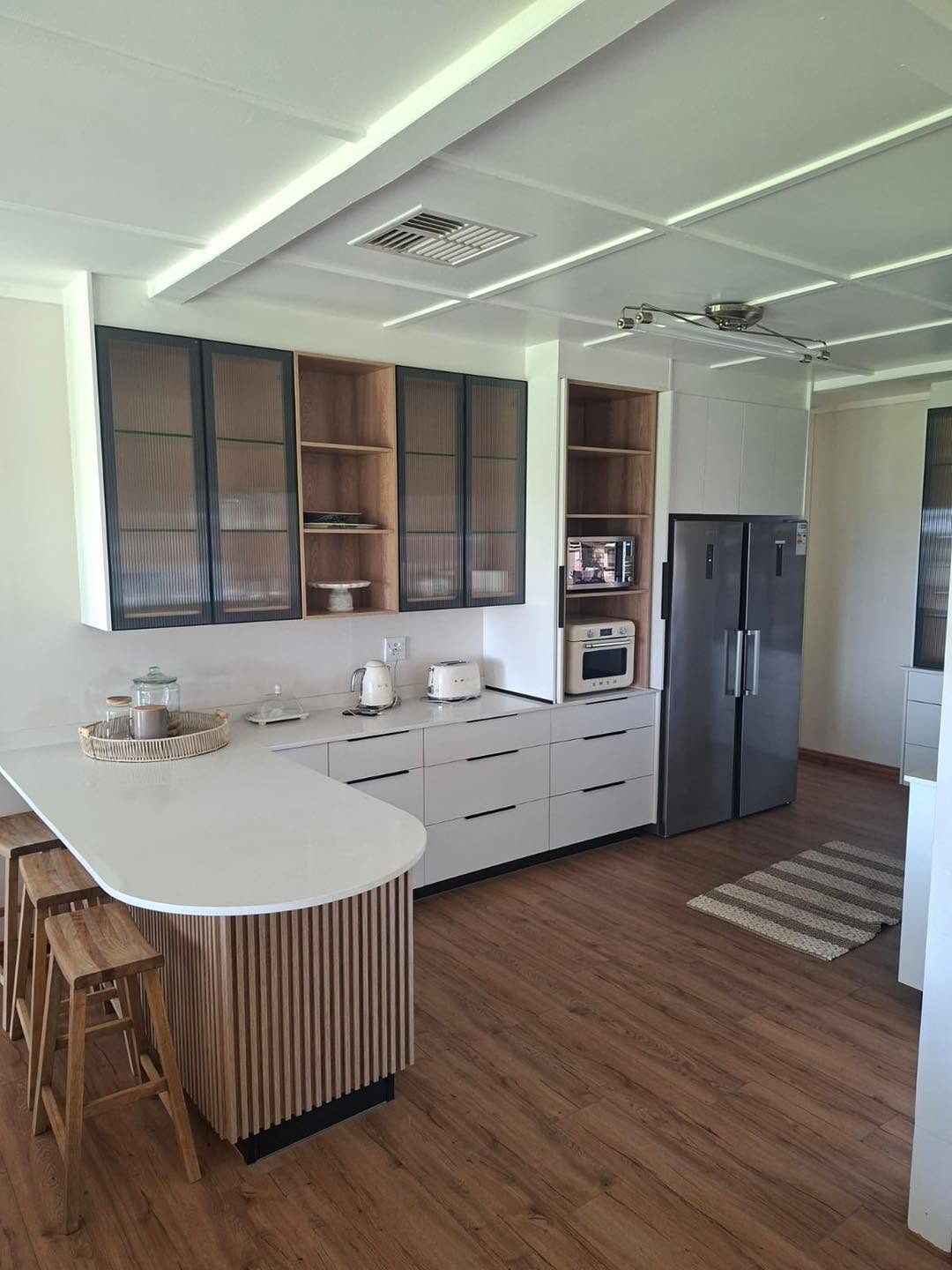 Custom Ilana Designs kitchen with fluted timber island, glass-fronted upper cabinets and quartz countertops
